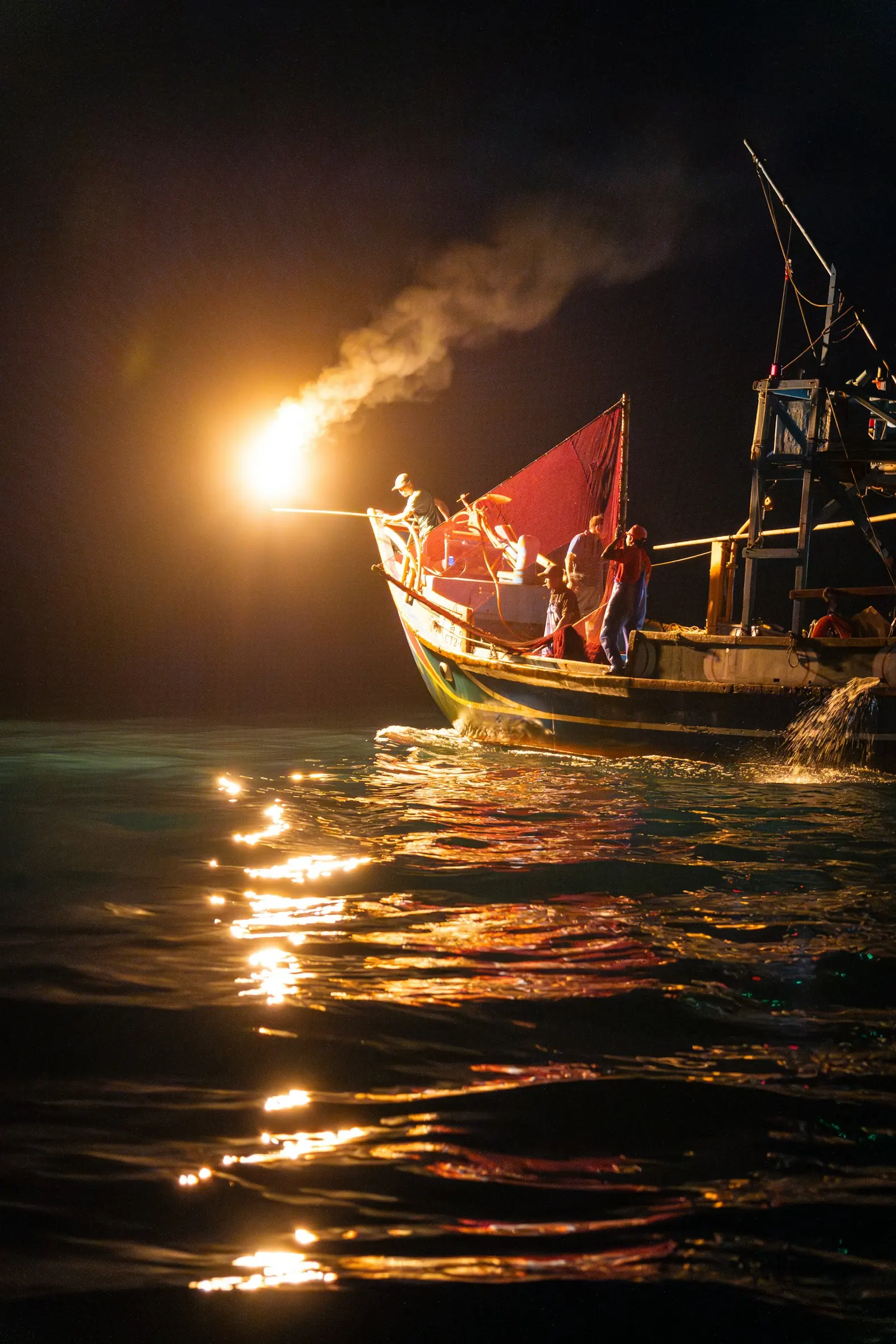 A working fishing boat lit at night on open water