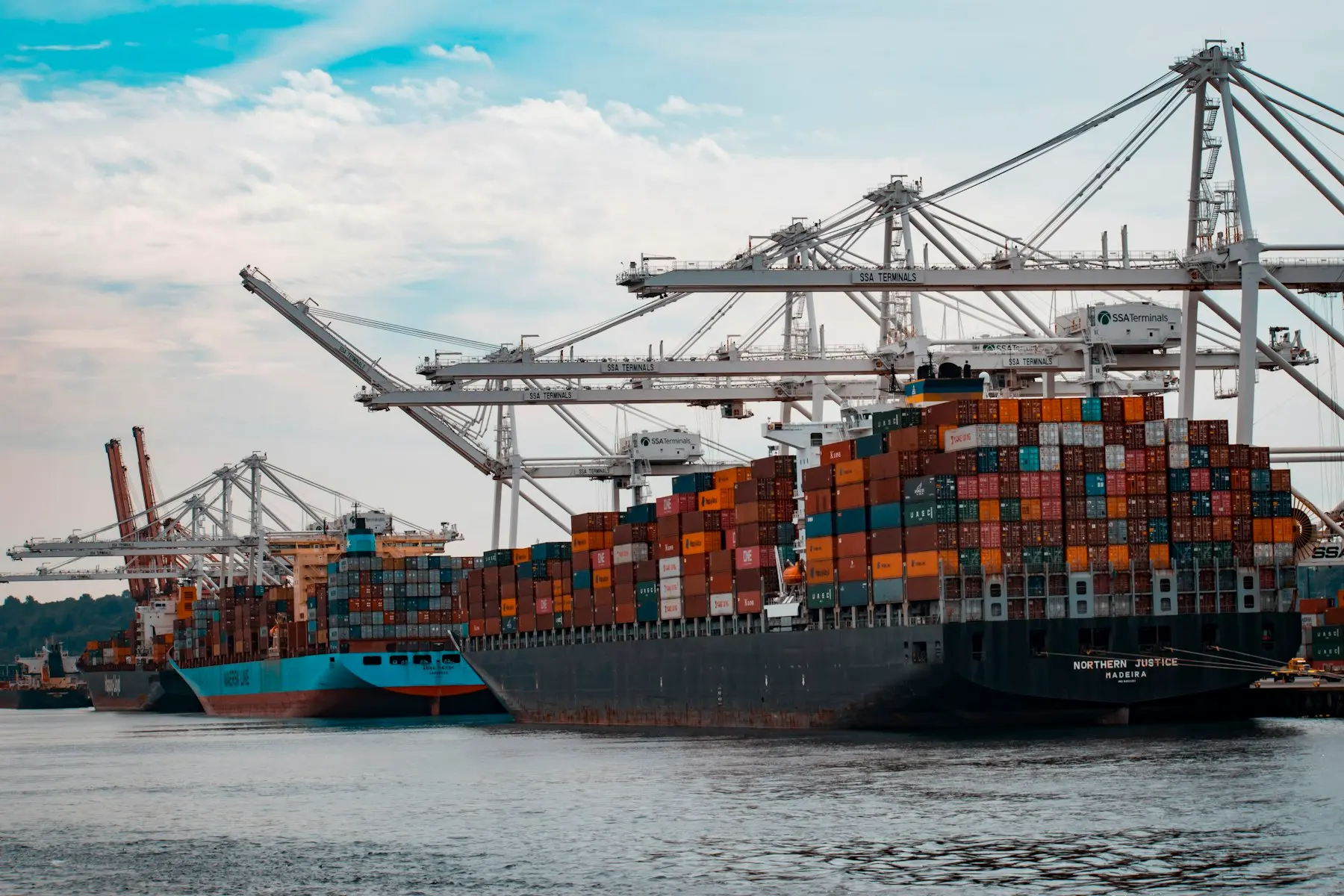 Container ships alongside cranes at a commercial port
